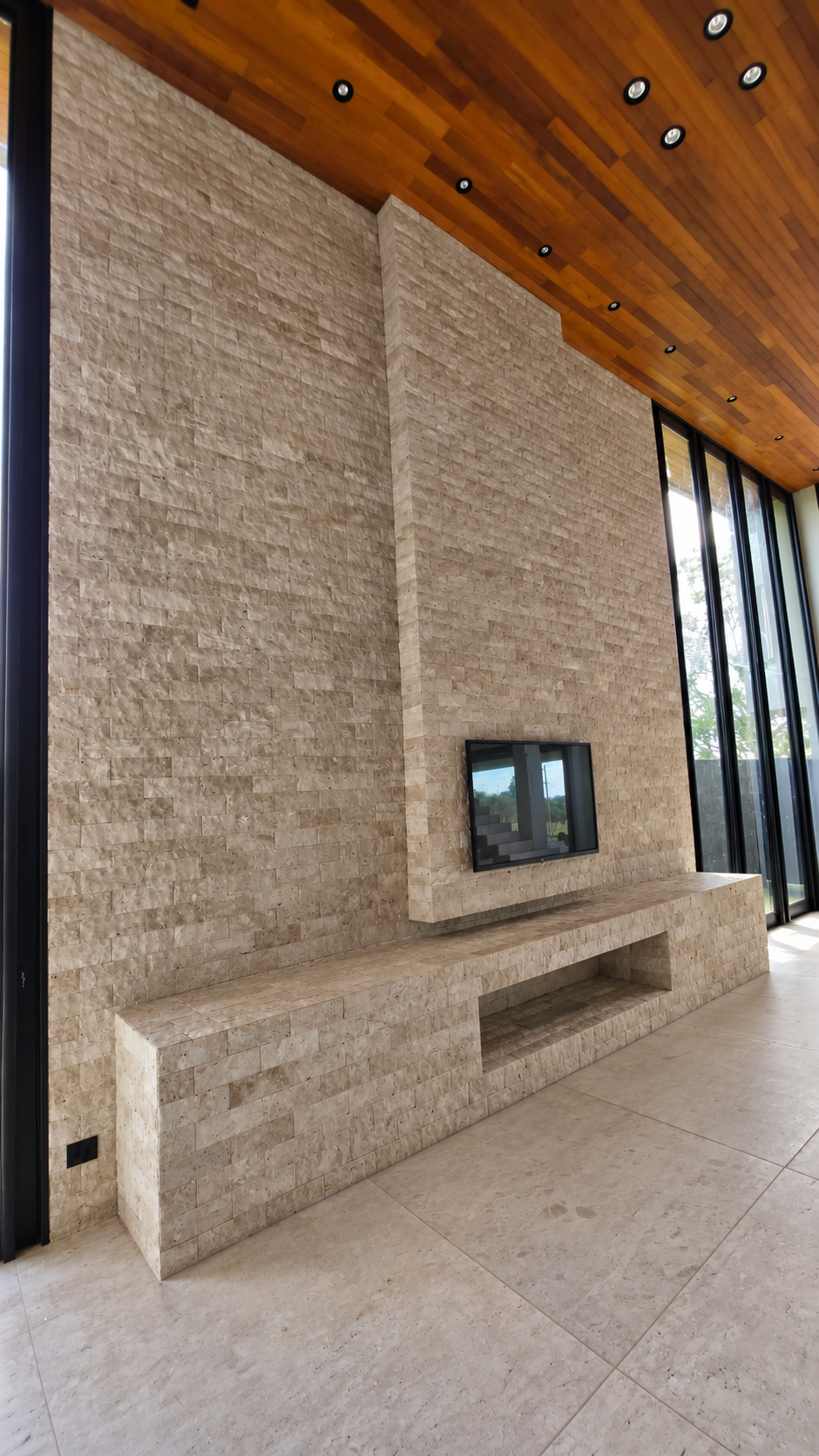 Ambiente com painel de TV em Travertino Rockface 10 × 30; entorno tratado digitalmente a partir de foto real